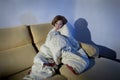 Young sick woman sitting on couch wrapped in duvet and blanket feeling miserable Royalty Free Stock Photo