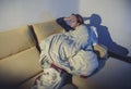 Young sick woman sitting on couch wrapped in duvet and blanket feeling miserable Royalty Free Stock Photo