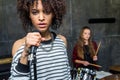 Young singer standing with microphone while friend playing drums