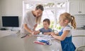 Young single caucasian mother helping her two cute little children with their homework in a bright kitchen. Two siblings Royalty Free Stock Photo