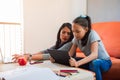 Young single mother helps her daughter with home studies on the tablet. Latin girls studying at home sitting on the sofa. Concept Royalty Free Stock Photo