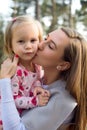 Young mother holding cute toddler girl daughter in her arms and giving her a kiss on a cheek Royalty Free Stock Photo