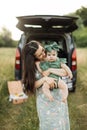 Young single mother holding on hands her little daughte,r standing on the grass during a picnic