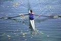 A Young single scull rowing competitor paddles on the tranquil l