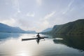 A Young single scull rowing competitor paddles on the tranquil lake