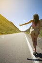 A young single woman of easy virtue, in light sexy clothes, voting on a highway in the desert, traveling alone Royalty Free Stock Photo