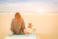 Young single woman sitting at beach with teddy bear