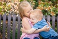 Young Sister and Brother Hugging On a Bench At The Park