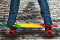 A young skateboarder in sneakers and jeans, standing on his skate. Closeup fragment of the skateboard and feet.