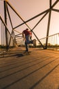 Young skateboarder on bridge at sunset