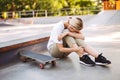 Young skater girl holding her painful leg and crying with skateboard near at skatepark isolated Royalty Free Stock Photo