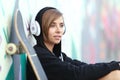 Young skater girl listening to the music with headphones