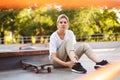 Young skater girl sadly looking in camera holding her painful leg with skateboard near while spending time at skatepark Royalty Free Stock Photo