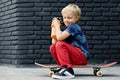 Young skater sit on skateboard, drink water from reusable bottle Royalty Free Stock Photo