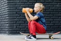 Young skater sit on skateboard, drink water from reusable bottle Royalty Free Stock Photo