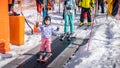 Young skier girl going up on conveyor lift belt to learn how to ski Royalty Free Stock Photo