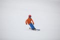 A young skier on the ski slope in a colorful orange and blue ski outfit