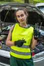 young skilled specialist mechanic woman in overalls and tools in hands near broken car.