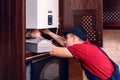 A young skilled worker regulates the gas boiler before use