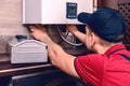 A young skilled worker regulates the gas boiler before use