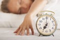 Young sleeping woman and alarm clock in bed