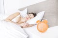 Young sleeping woman and alarm clock in bedroom at home Royalty Free Stock Photo
