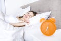 Young sleeping woman and alarm clock in bedroom at home Royalty Free Stock Photo