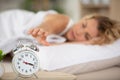 young sleeping woman and alarm clock in bedroom at home Royalty Free Stock Photo