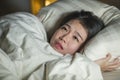 Young sleepless beautiful and scared Asian Chinese woman lying on bed awake at night suffering nightmare after watching zombie