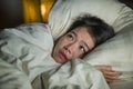 Young sleepless beautiful and scared Asian Japanese woman lying on bed awake at night suffering nightmare after watching zombie