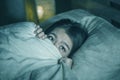 Young sleepless beautiful and scared Asian Japanese woman lying on bed awake at night suffering nightmare after watching zombie
