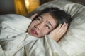 Young sleepless beautiful and scared Asian Korean woman lying on bed awake at night suffering nightmare after watching zombie