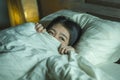 Young sleepless beautiful and scared Asian Korean woman lying on bed awake at night suffering nightmare after watching zombie