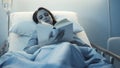 Young sleepless patient lying in the hospital bed and reading a book