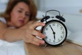 Young sleepy woman trying to turn off the alarm clock Royalty Free Stock Photo