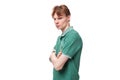 a young slender ginger man with a tattoo on his arm, dressed in a green T-shirt stands sideways Royalty Free Stock Photo