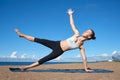 Young slender girl doing yoga on the beach on a sunny morning, plank exercise, healthy lifestyle Royalty Free Stock Photo