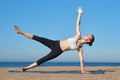 Young slender girl doing yoga on the beach on a sunny morning, plank exercise, healthy lifestyle Royalty Free Stock Photo