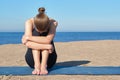 Young slender girl doing yoga on the beach on a sunny morning, sad mood, sad thoughts Royalty Free Stock Photo