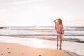 A young slender girl stands alone on the beach or ocean and look at the horizont. A woman dressed in a warm sweater Royalty Free Stock Photo