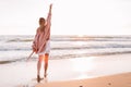 A young slender girl stands alone on the beach or ocean and look at the horizont. A woman dressed in a warm sweater. Warm fall, Royalty Free Stock Photo