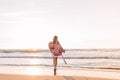 A young slender girl stands alone on the beach or ocean and look at the horizont. A woman dressed in a warm sweater. Toned Royalty Free Stock Photo