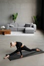 A young slender woman does splits to stretch her legs. Joyful talented woman doing twine in the living room of the house. Healthy