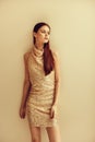 Young slender woman in gold sequined dress with open back, disco party style Christmas look