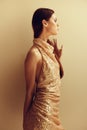 Young slender woman in gold sequined dress with open back, disco party style Christmas look