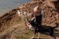 Rear View Of Woman With Dog Sitting On Hill Against Sea At Sunset. Royalty Free Stock Photo