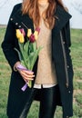 Young slender woman in an overcoat standing on a green meadow an