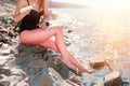A young slender woman smears sunscreen on the beach. Redness skin on legs. The concept of protection from the sun and unwanted