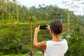 A young slender woman stands with phone on rice terraces on the popular tourist island of Bali Royalty Free Stock Photo