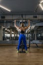 Young slender woman in tight leggings trains in the gym. Back view. Upper block thrust. Vertical frame